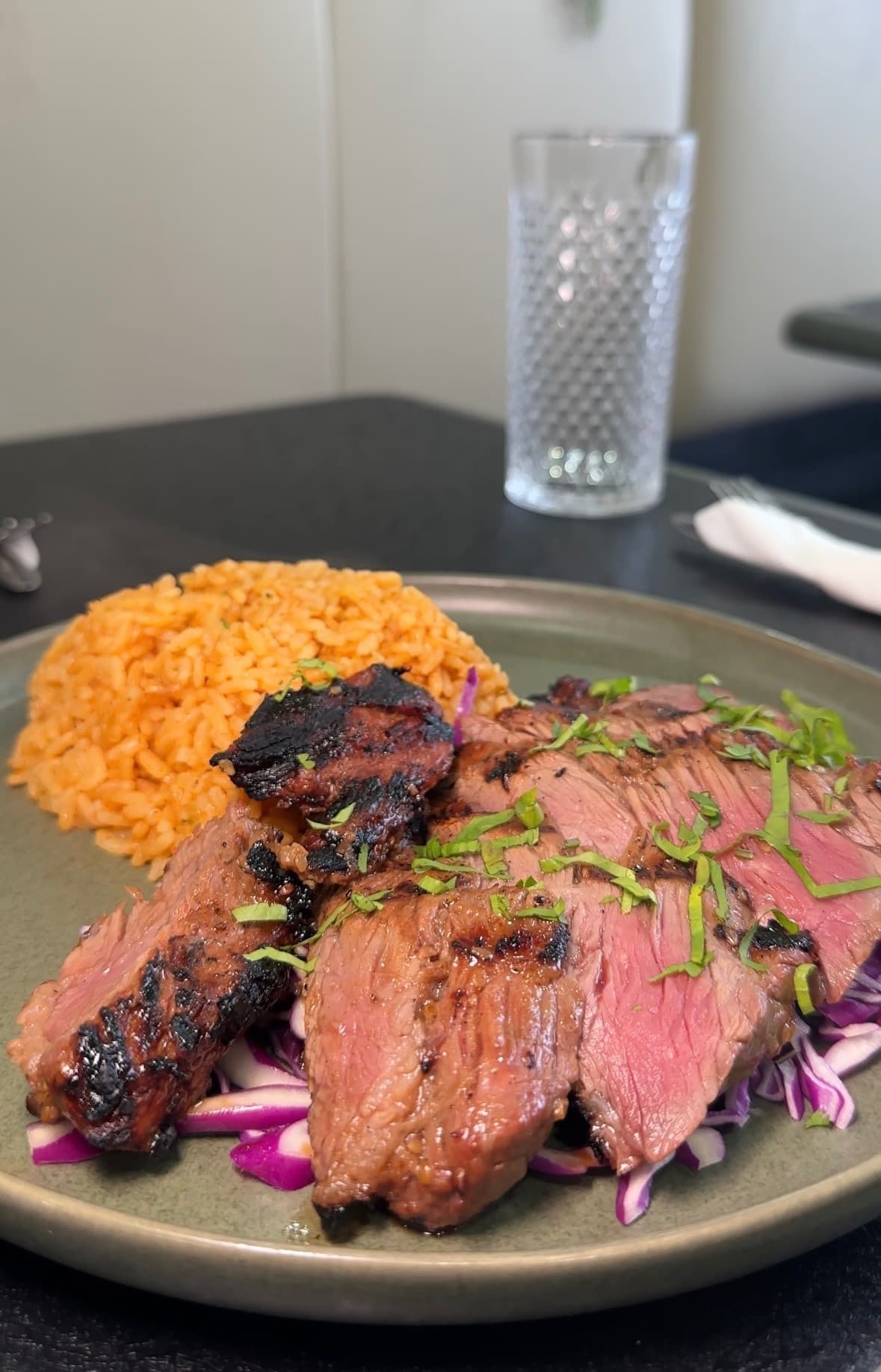 Sliced Hawaiian flap steak fanned over red cabbage slaw
