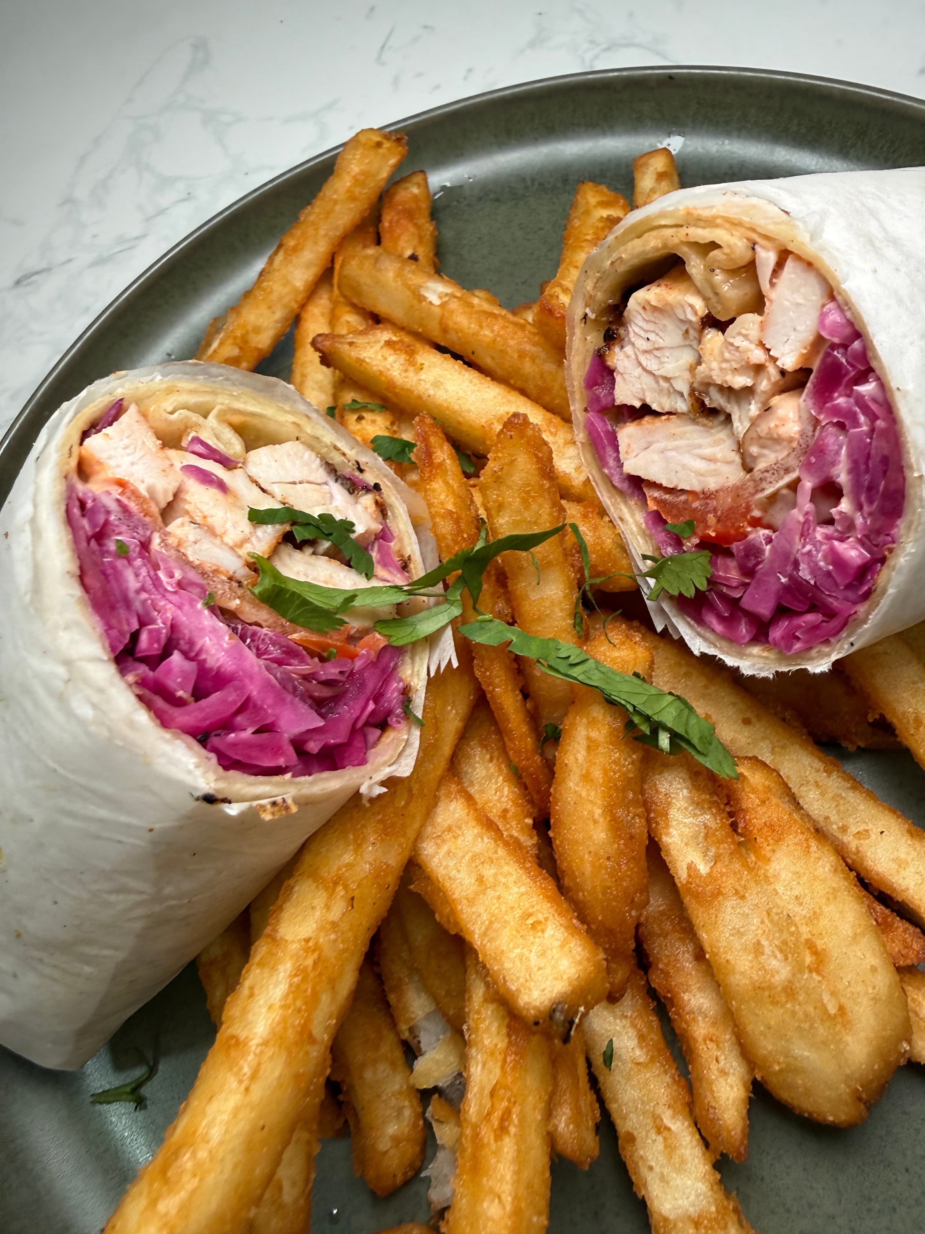Dominican style chimi wrap sliced to show grilled chicken and pickled cabbage